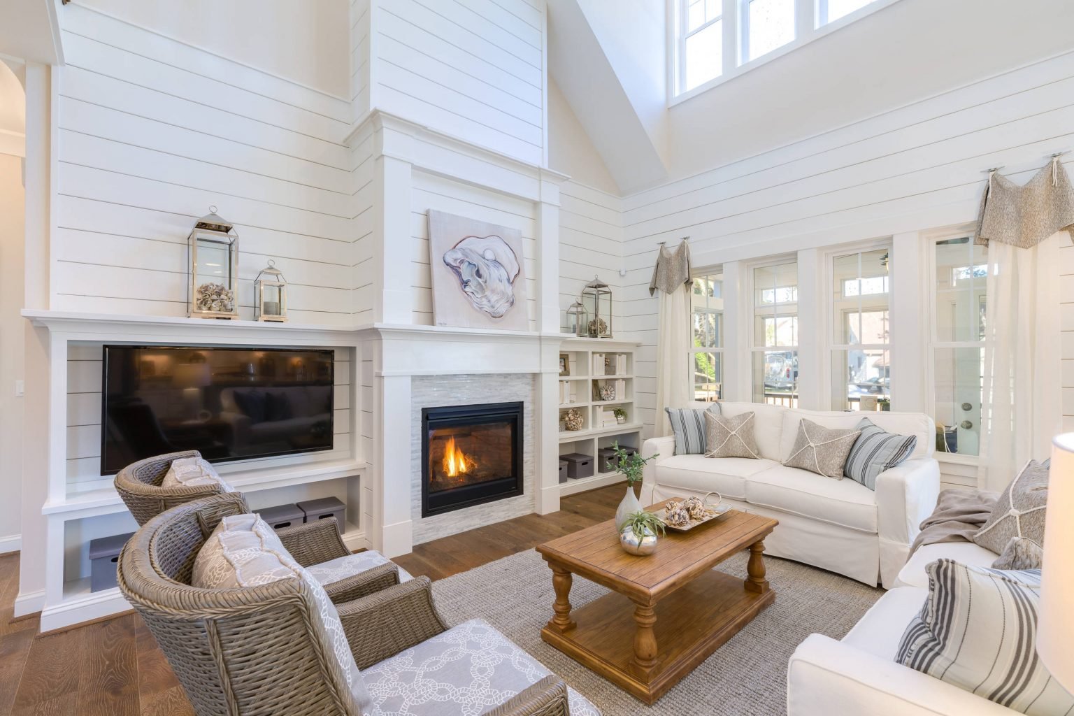 Bright living room with a fireplace, tall windows, and neutral furnishings
